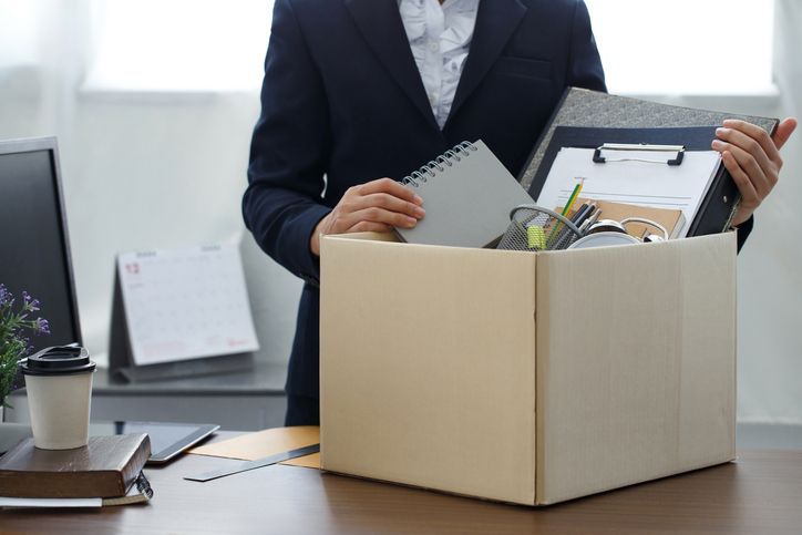 Vrouw ruimt de spullen op haar bureau op in een doos