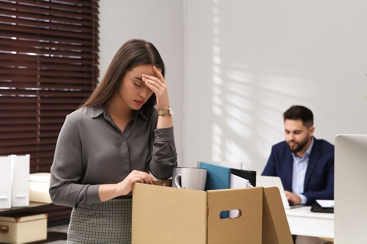 vrouw die net is ontslagen, steunt haar arm op een doos met haar spullen